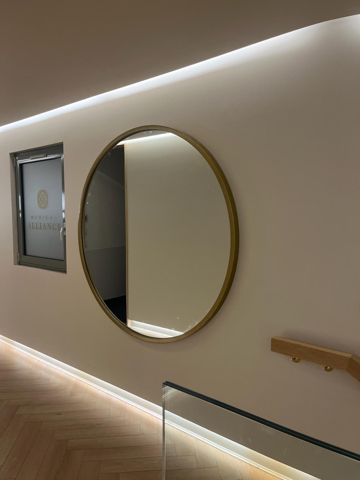 Miroir rond et éclairage indirect dans une circulation du centre esthétique